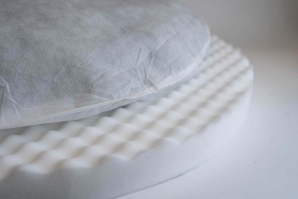 A soft pillow sits on top of a thick layer of orthopedic foam, demonstrating Snoozer's blend of comfort and support in orthopedic beds.